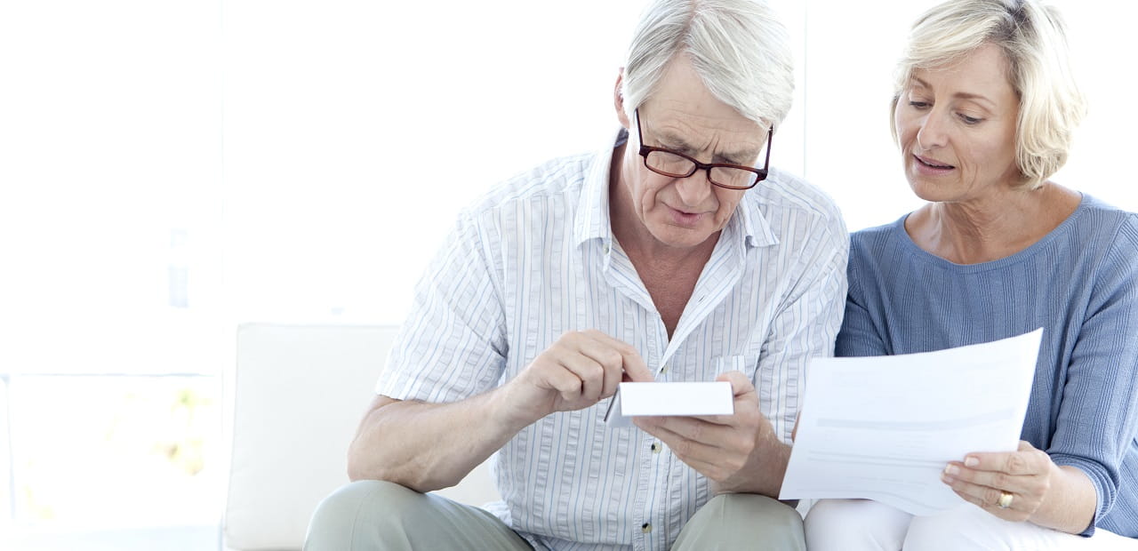 Senior couple seated together looking at documents.